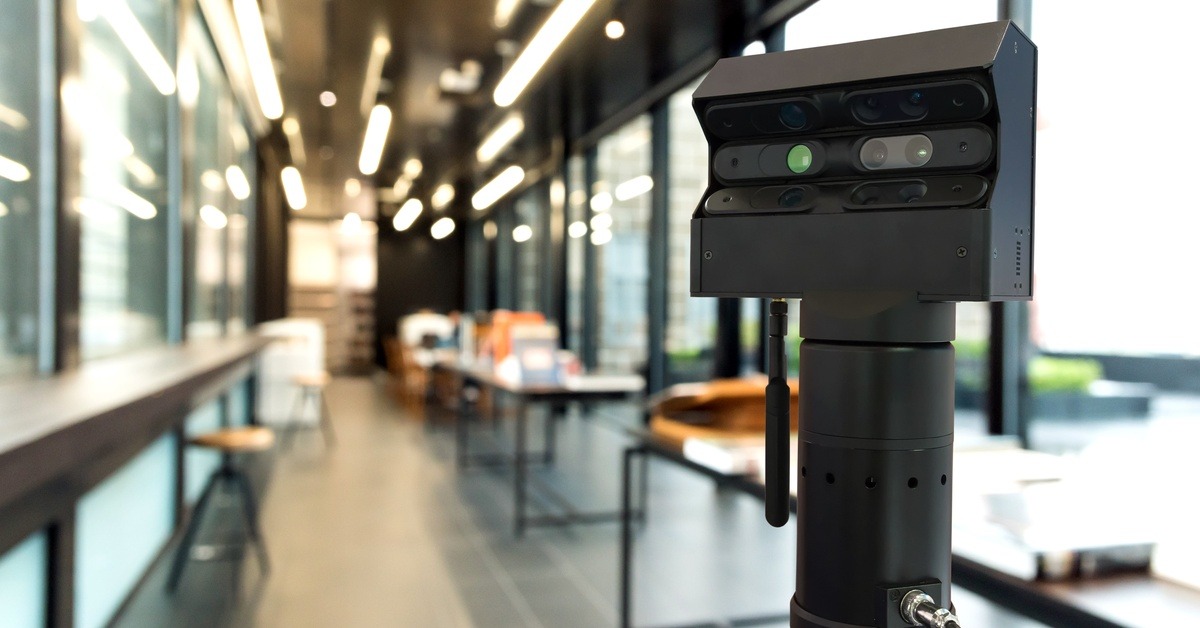 A 3D scanner set up in a long hallway. The background is blurred, but you can see a few tables behind the scanner.