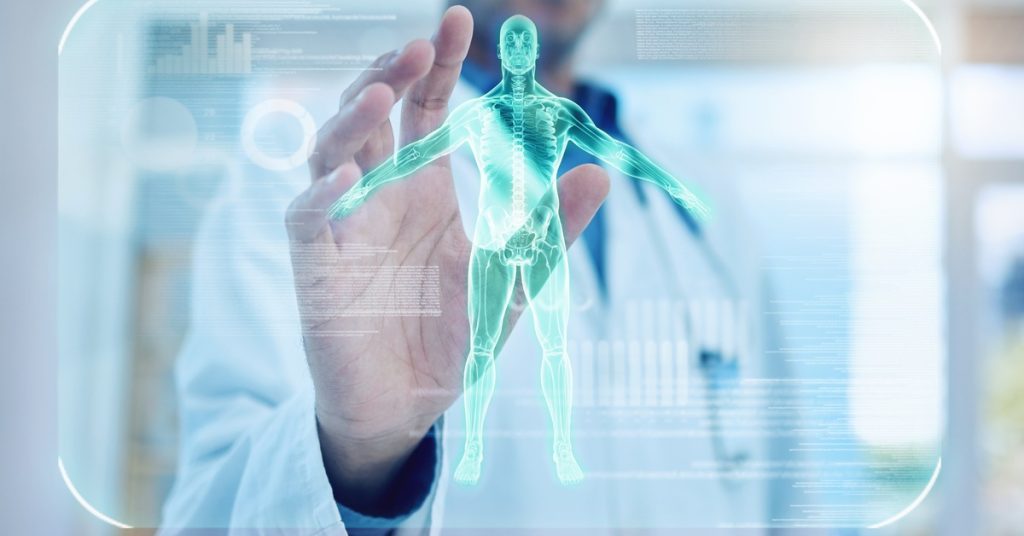 A doctor in a lab coat reaching out with one hand towards the camera. There is a graphic of a skeletal system in front of him.