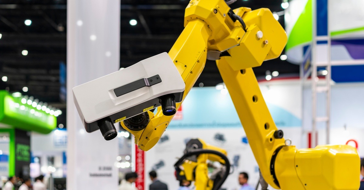 A 3D laser scanner attached to a large yellow arm. The scanner is currently facing downward at something below it.